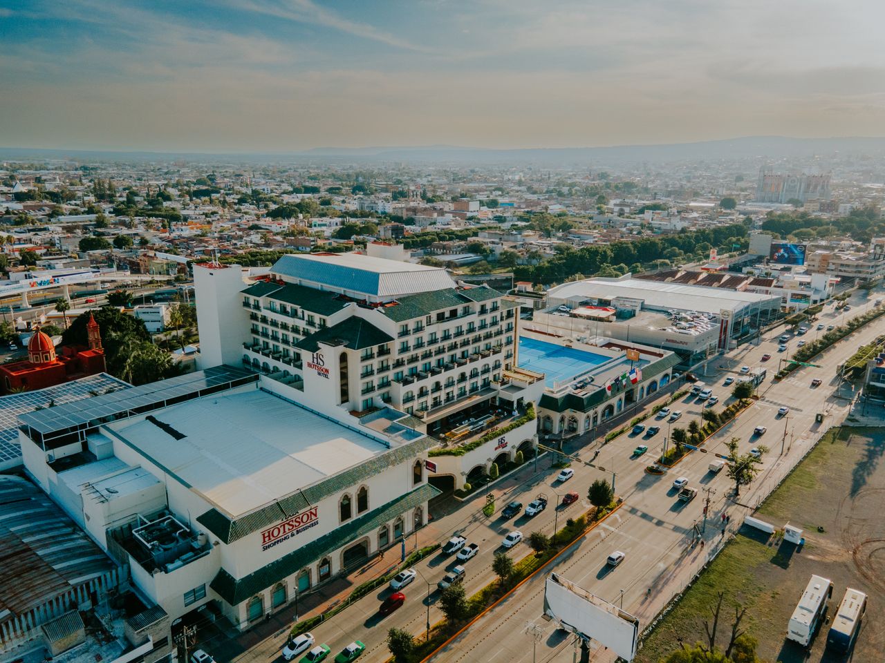 Drone shot capturing a vibrant cityscape with prominent hotel and busy highway.