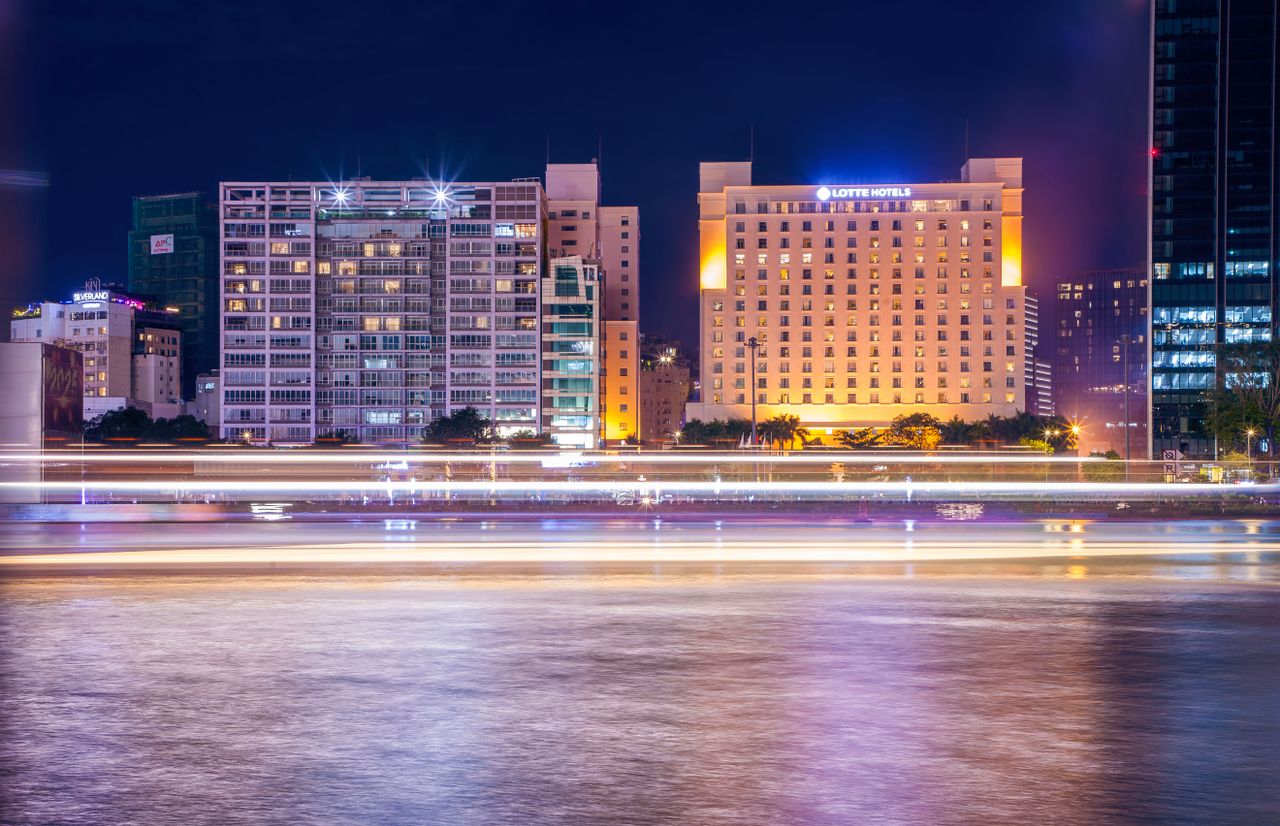 Lotte Hotels illuminated at night with motion lights on a calm riverfront.