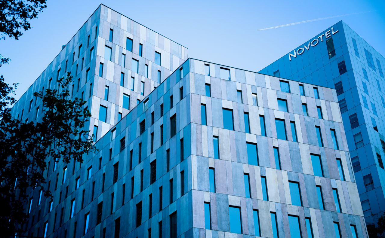Blue-toned modern architecture of Novotel in Barcelona under a clear sky.